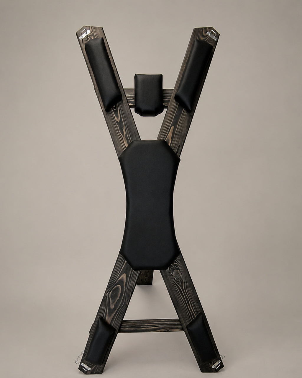 Front view of a freestanding St. Andrew’s Cross in dark-finished spruce with black padded supports