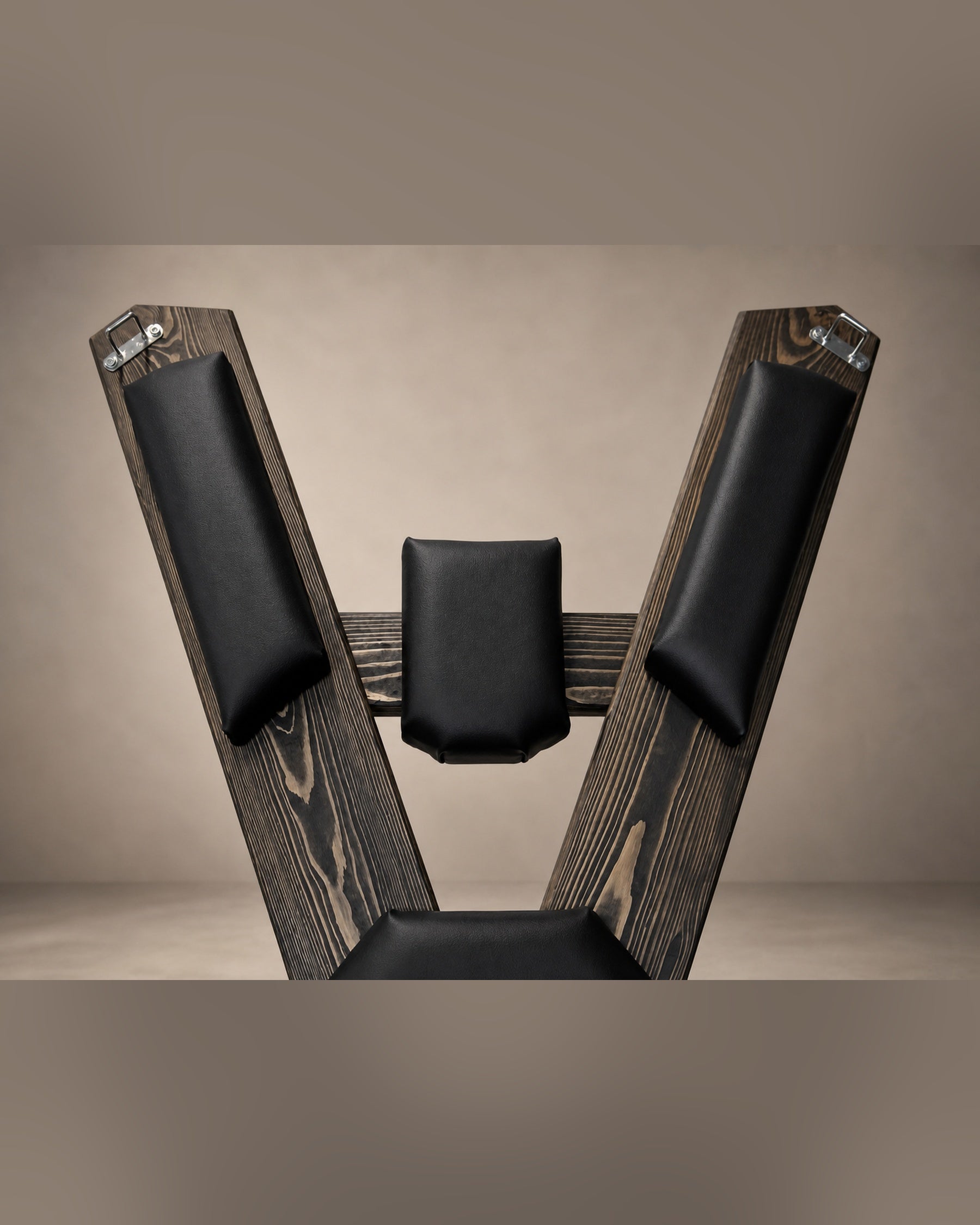 Upper section of the St. Andrew’s Cross showing black padded supports, visible wood grain and metal attachment points