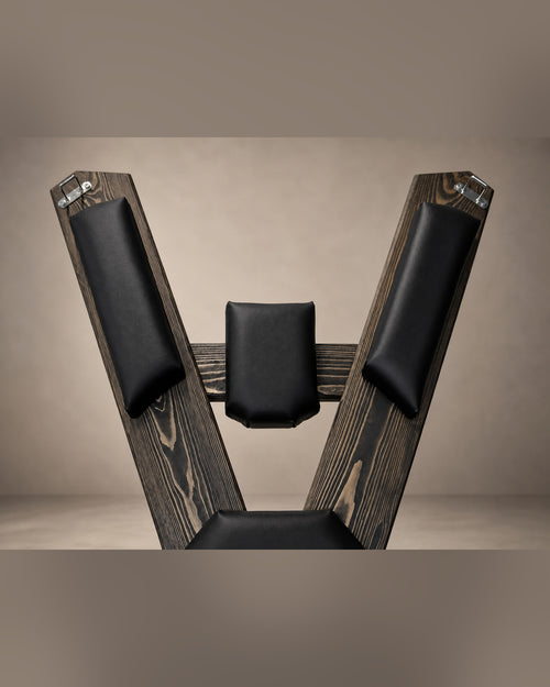 Upper section of the St. Andrew’s Cross showing black padded supports, visible wood grain and metal attachment points